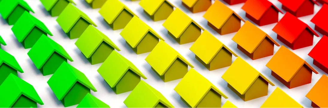 Reihen kleiner Häuser in Farbverläufen von Grün über Gelb zu Rot als Symbol für Energieeffizienzklassen